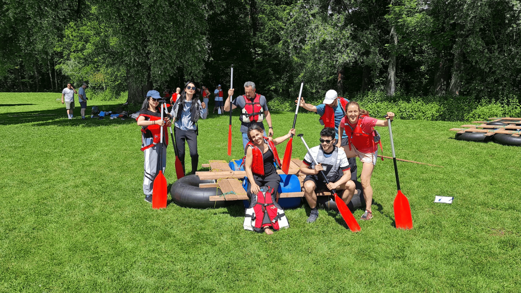 Gruppe mit Schwimmwesten und Paddeln vor dem Start ins Floßbau-Teamevent